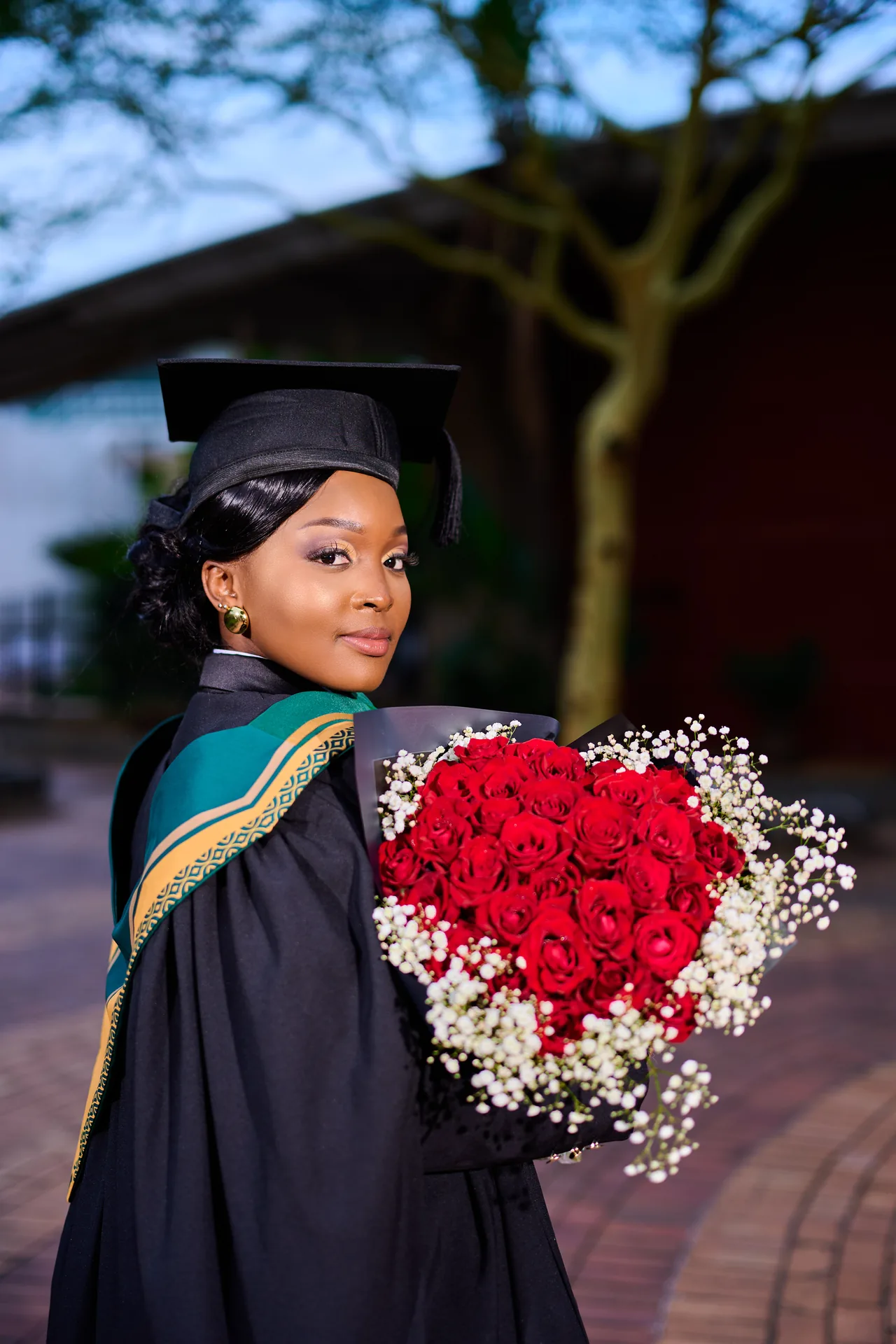 Graduate celebrating with a bouquet of red roses